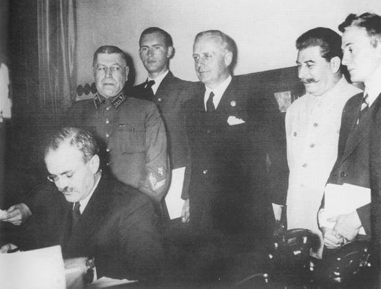 Й.Сталін, Й.Ріббентроп (другий і третій праворуч) і В.Молотов (сидить) під час підписання Договору про ненапад між Німеччиною та Радянським Союзом. Москва, 1939 р.